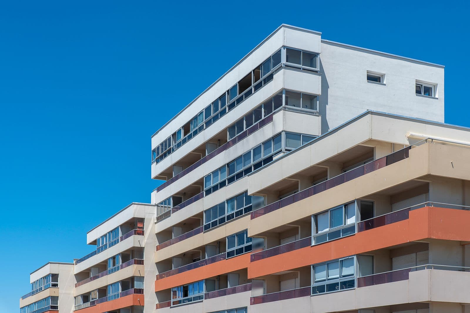 Modern multi-storey residential apartment building with balconies against blue sky