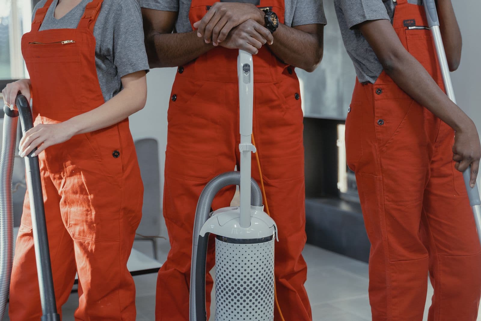 Three workers in coveralls with cleaning tools